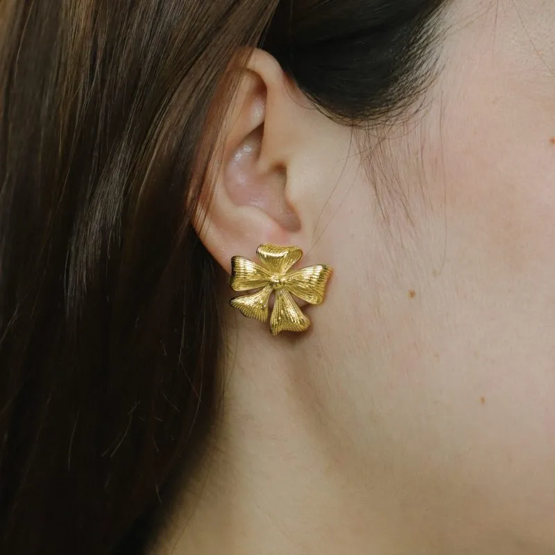 Female model wearing 18K gold-plated flower stud earrings to showcase fit for Established brands