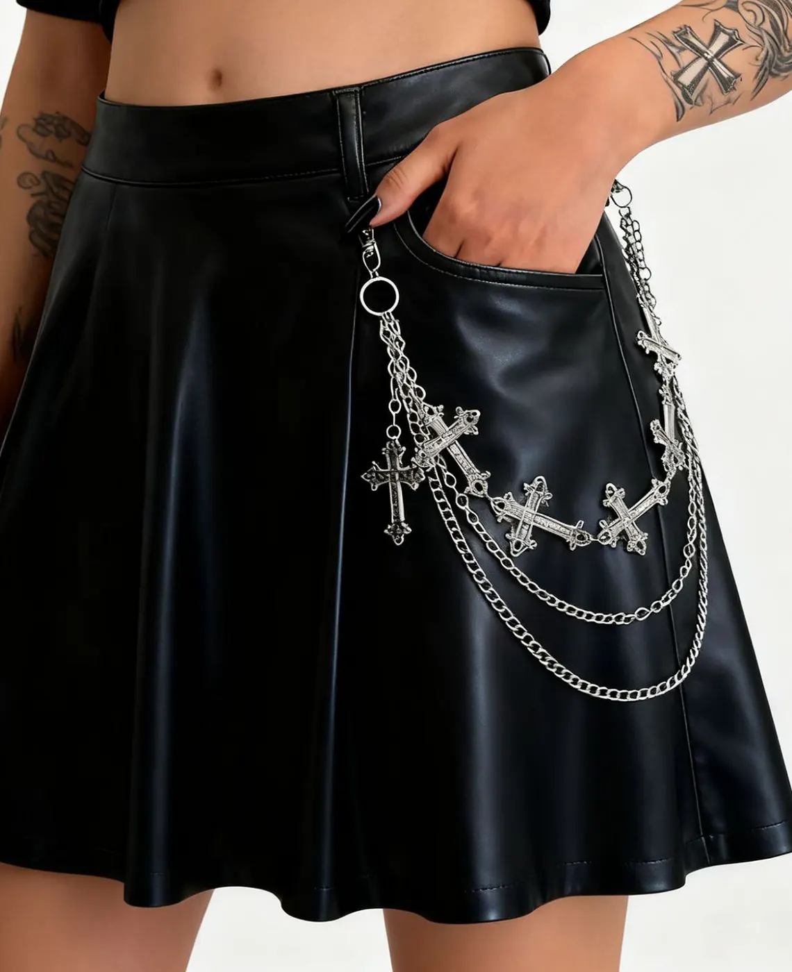Layered silver cross chain on black faux leather miniskirt