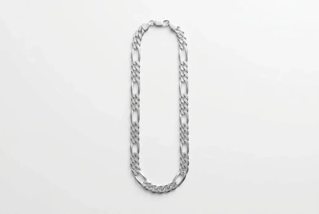 Custom polished figaro chain with rectangular clasp, laid flat in elongated oval on white background – alternating short and long oval links with bright silver luster. B2B ready for OEM/ODM orders, ideal as base chain for charm bracelets or standalone necklaces.