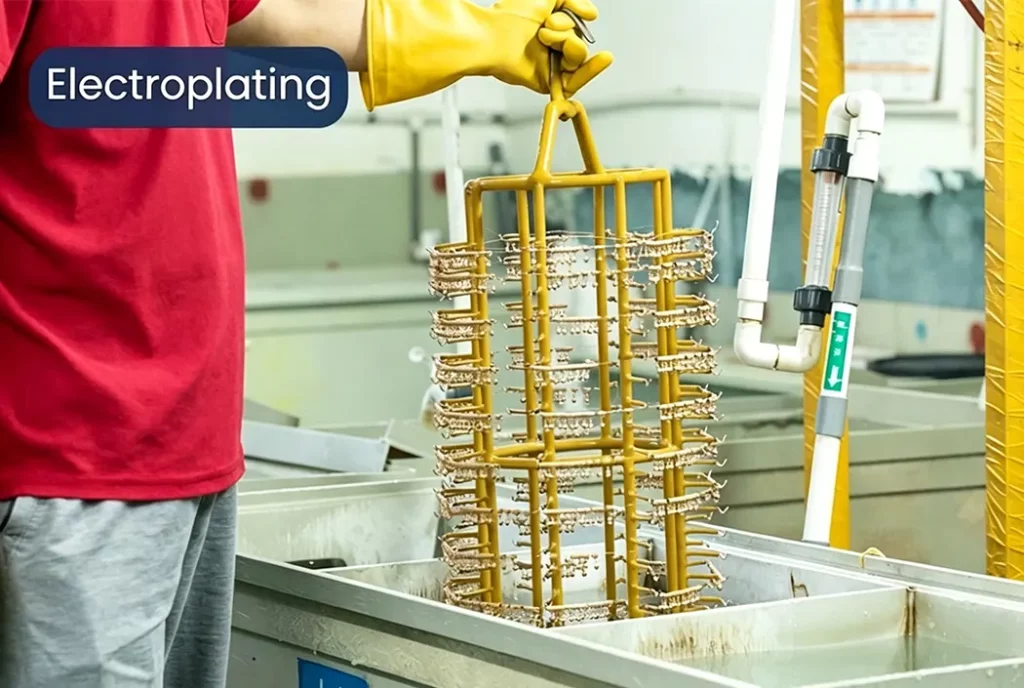 A worker is placing copper jewelry intended for electroplating into a cleaning tank.