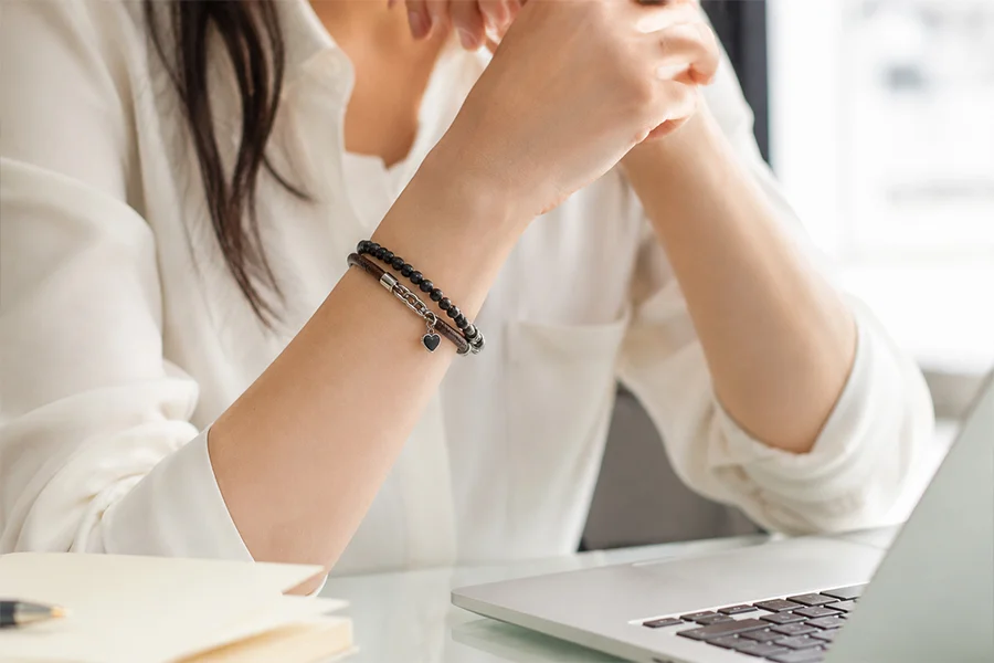 Woman wearing a custom charm bracelet in an everyday office setting. As a professional sports jewelry manufacturer, we design stylish bracelets that seamlessly blend into daily and casual wear.