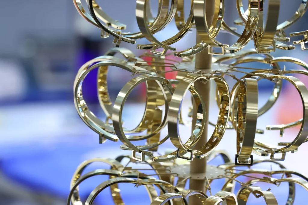 Gold PVD-plated stainless steel bracelets on a factory display rack, industrial metal plating process, shiny durable fashion accessories