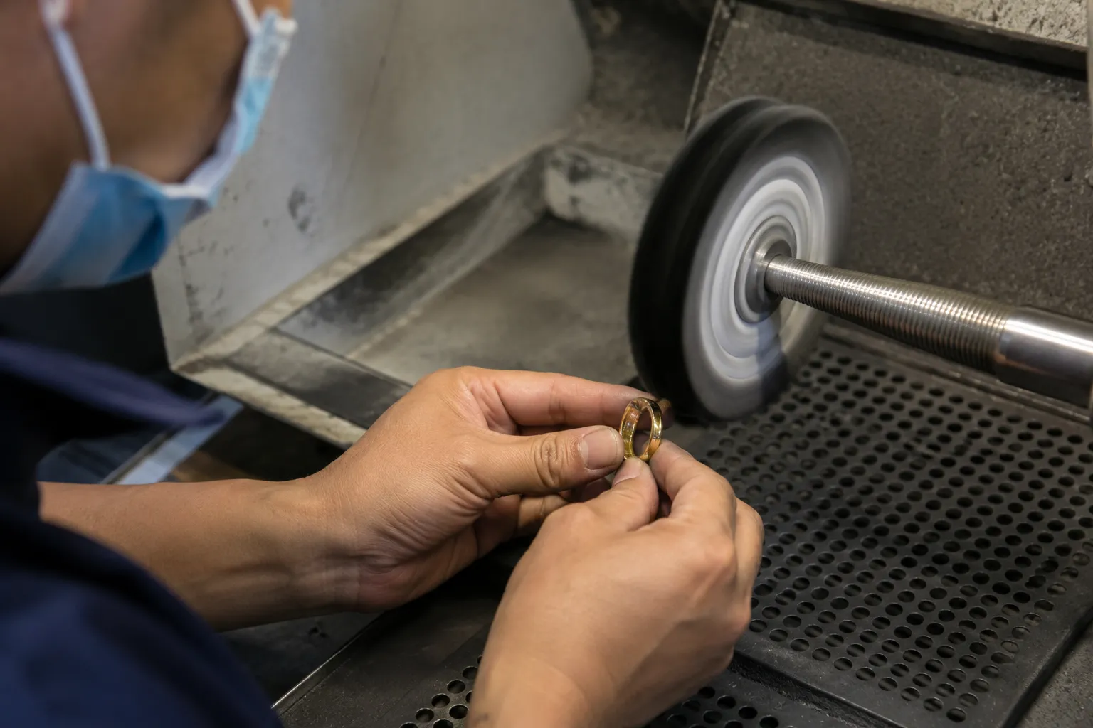 Jewelry worker polishing a stainless steel ring during surface preparation before PVD coating, creating a mirror-like finish for long-lasting jewelry plating.