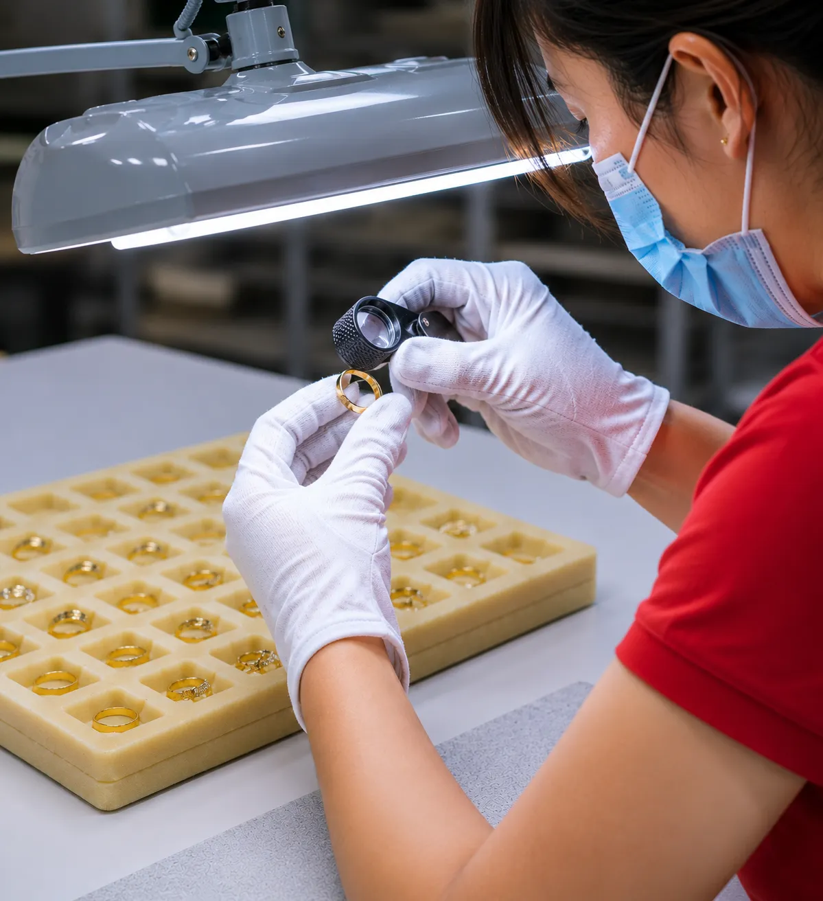 Jewelry quality inspector checking a stainless steel ring after polishing to ensure structural integrity and defect-free quality.
