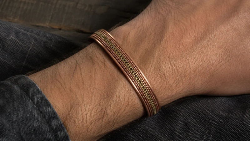 Male wrist wearing an antique copper and brass braided cuff bracelet