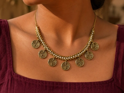 Model wearing a custom brass pearl and coin pendant necklace produced by an OEM brass necklace manufacturer