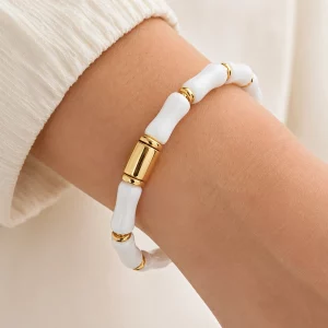 Close-up of a custom white segmented bangle bracelet with gold connectors worn on a model’s wrist for private label jewelry development.