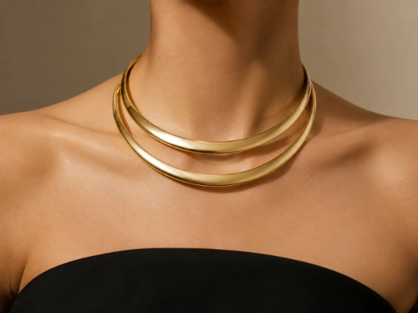 Female model wearing a polished double-layer brass collar necklace with a black strapless dress.