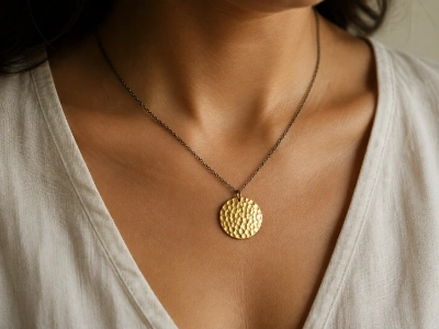 Model wearing a custom hammered brass disc pendant necklace made by an OEM brass necklace manufacturer