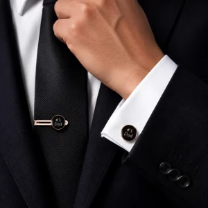 Rose gold custom cufflinks and matching tie clip displayed with a black suit and tie.