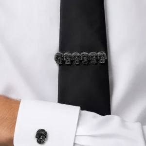 Black skull cufflinks and matching skull tie clip displayed on a white shirt and black tie.