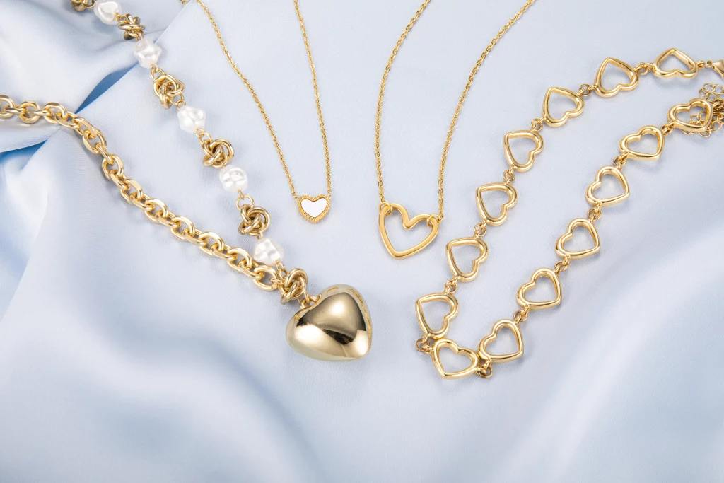 Gold-tone layered heart necklaces featuring a crystal heart pendant, turquoise-colored heart charm, and pearl accent