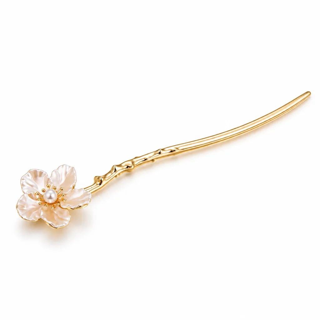 Gold-tone floral hair stick with an iridescent five-petal flower, pearl center, and decorative branch detail on a white background.