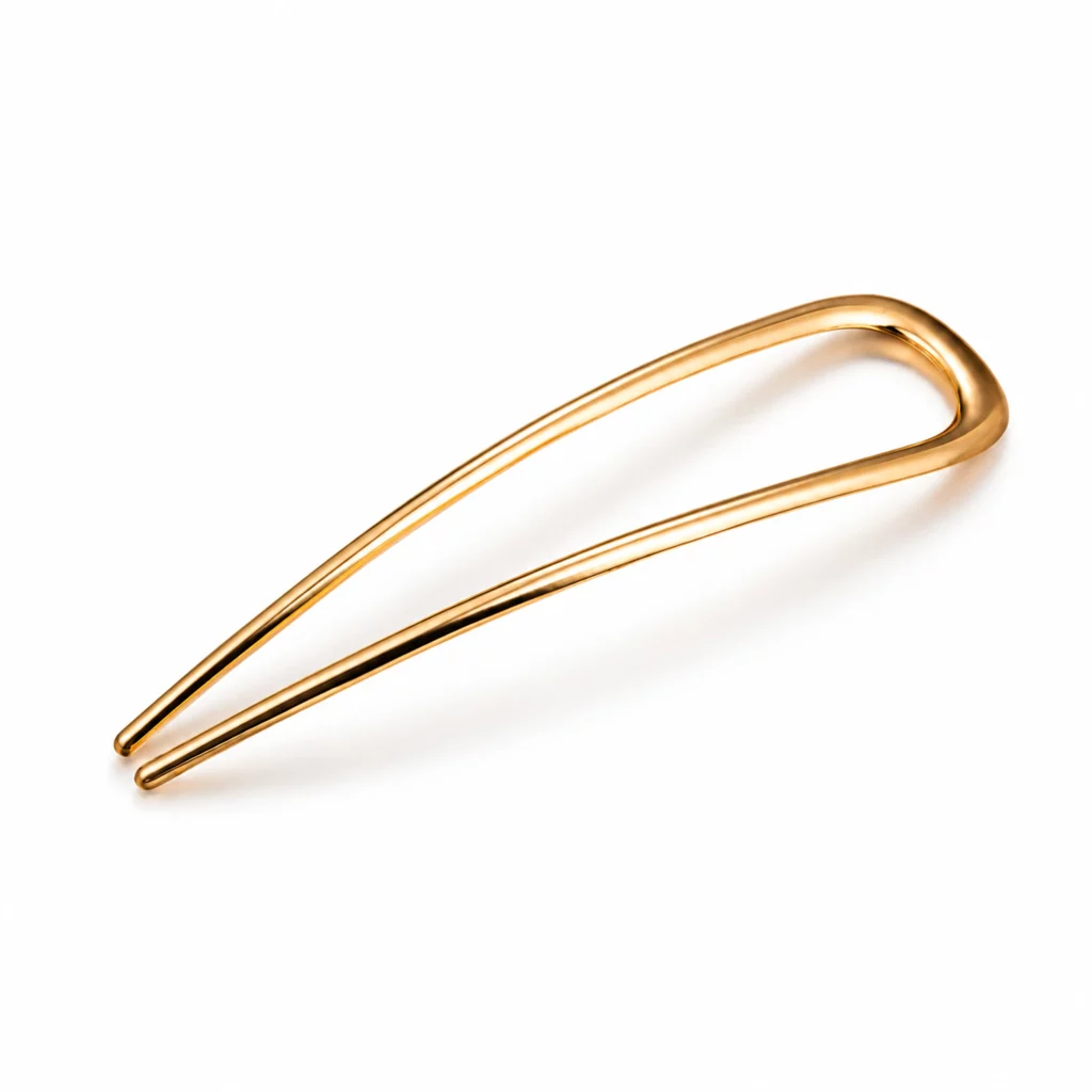 Gold-tone U-shaped two-prong hair fork with a smooth polished surface and minimalist curved design on a white background.