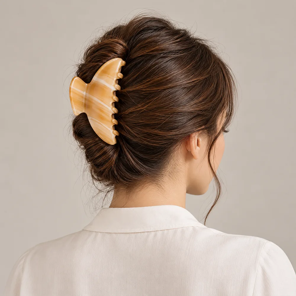 Honey striped cellulose acetate hair claw clip securing a French twist hairstyle.