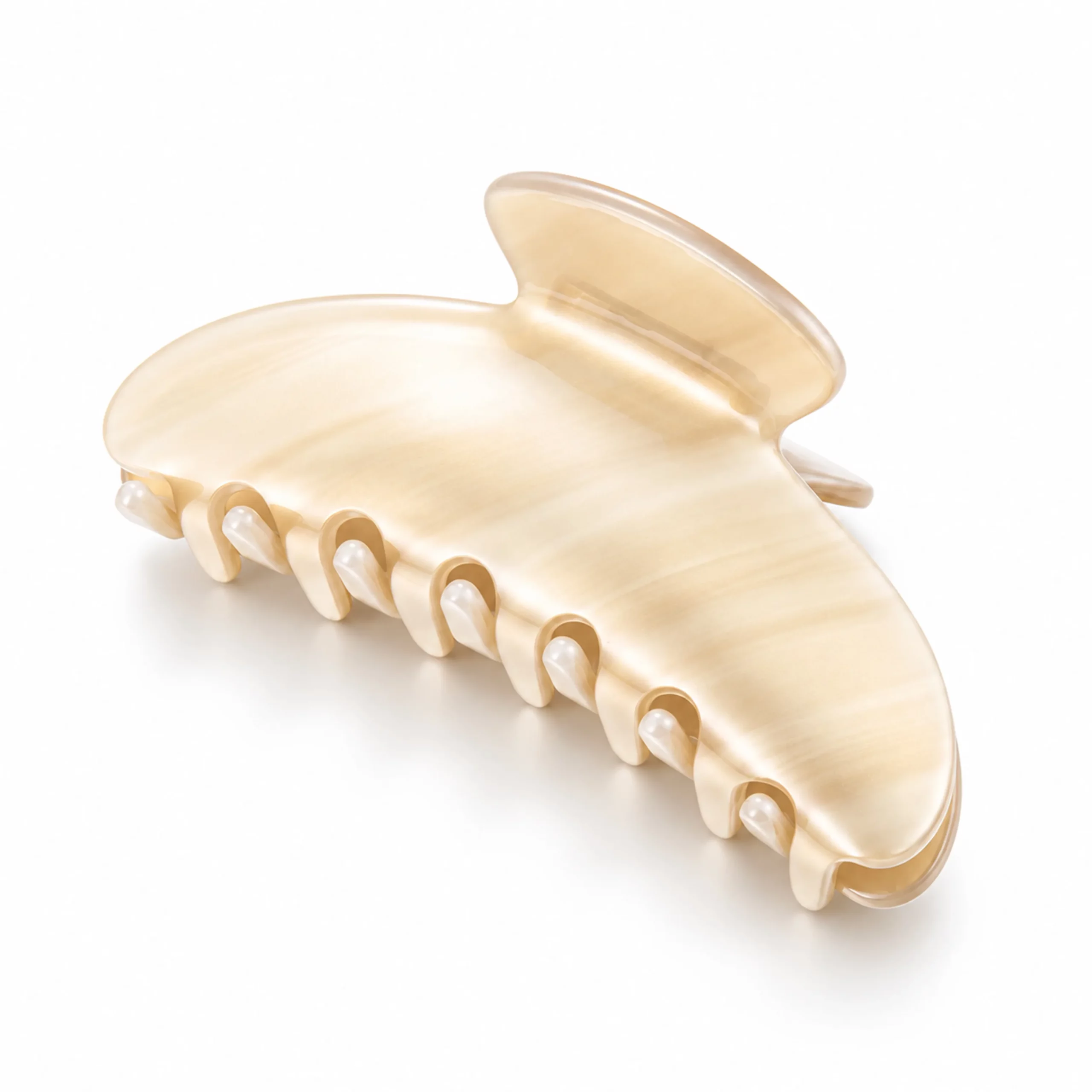 Ivory cream cellulose acetate hair claw clip with soft marbled texture and polished curved surface.